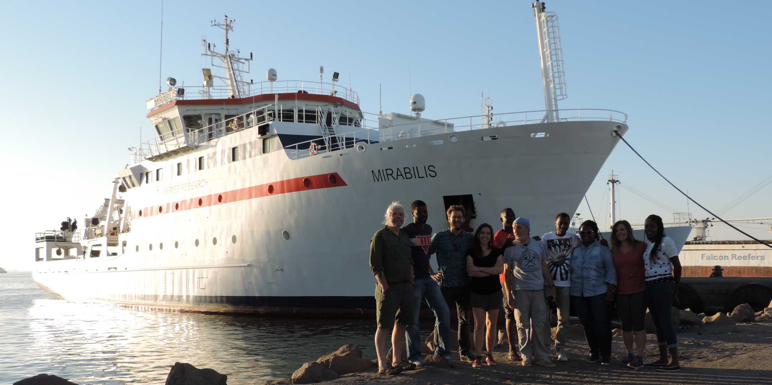 team in front of research vessel